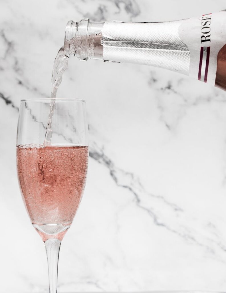 Close-up of rosé champagne being poured into a flute against a marble background.