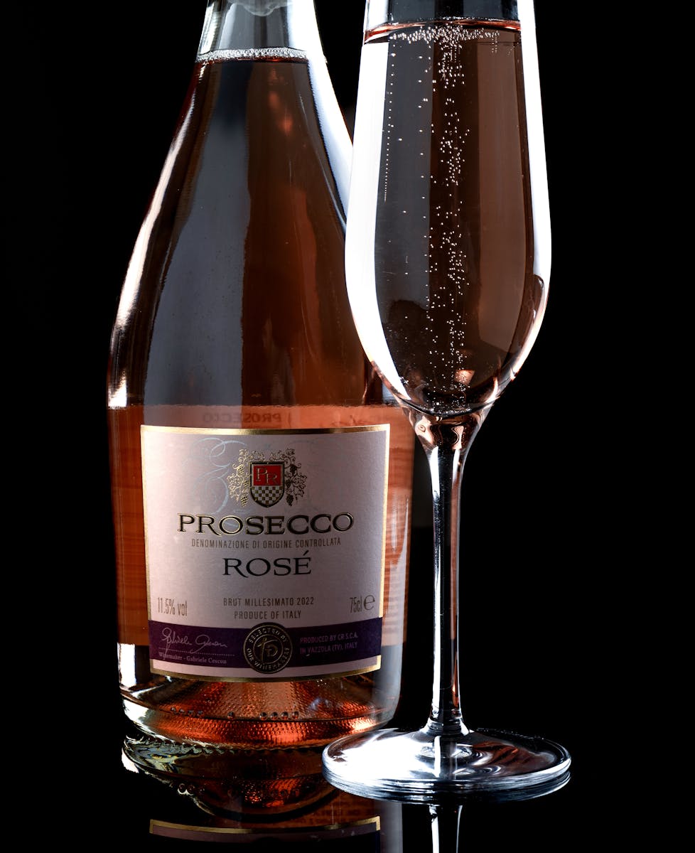 Close-up of a Prosecco Rosé bottle with a filled flute glass, showcasing sparkling bubbles.