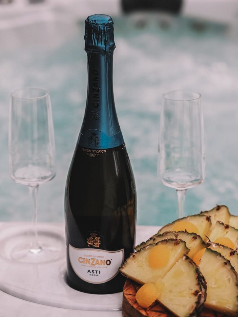 Close-up of a Cinzano Asti bottle with pineapple slices and empty wine glasses on a table.